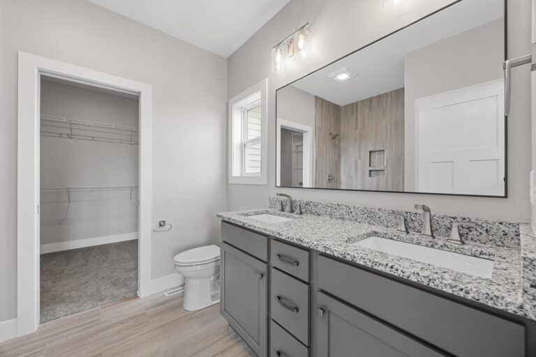 bathroom with double sink next to walk in closet