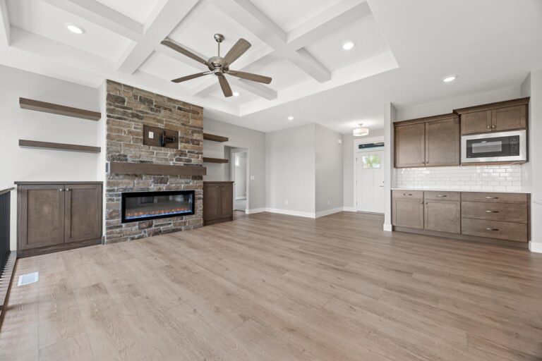 living room with coffered ceiling, ceiling fan, bricked gas fireplace