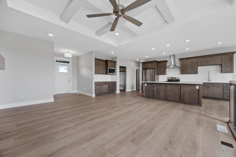 living room with coffered ceiling and ceiling fan open to kitchen